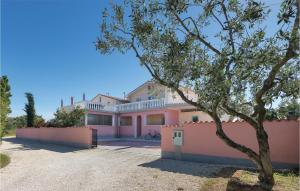ein großes rosafarbenes Haus mit einem Baum davor in der Unterkunft Two-Bedroom Apartment In Peroj in Peroj