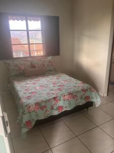 a bedroom with a bed with a floral comforter at Apartamento Alecrim in São Roque de Minas
