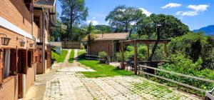 a stone walkway between two buildings next to a house at Cores e Flores da Serra Pousada by Concavus in Santo Antônio do Pinhal +20 photos