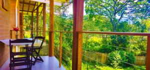 a balcony with a table and a view of a forest at Cores e Flores da Serra Pousada by Concavus in Santo Antônio do Pinhal