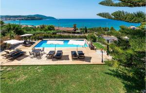 a swimming pool with chairs and umbrellas and the ocean at Amazing Apartment In Agropoli With Wifi in Agropoli