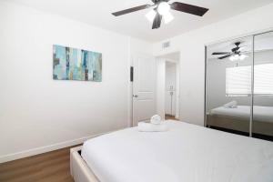 a white bedroom with a bed and a ceiling fan at 2BR Plus Bonus Room and Pool Access Near Universal Studios in Los Angeles +37 photos