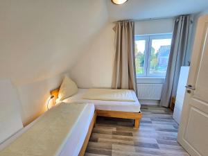 um pequeno quarto com duas camas e uma janela em Sechendorf Ferienhaus Solängen Sechendorf em Blekendorf