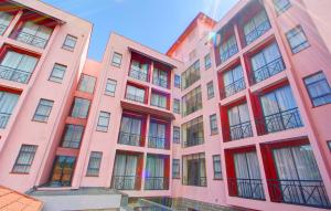 un edificio de apartamentos de color rosa con ventanas rojas en Vittoria Suites en Kisumu