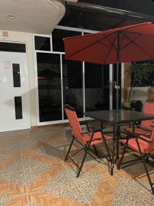 a table and chairs with a red umbrella at Galex Hotel Posada in Huajuapan de León +3 photos