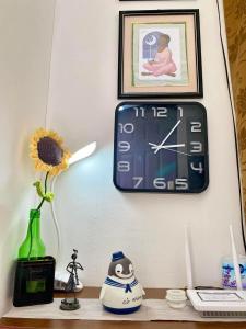 a clock on a wall above a shelf with a flower at RANDA HOMESTAY at Grandville Subd Dalipuga Iligan in Iligan City