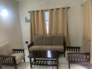 Una sala de estar con un sofá y dos sillas y una mesa. en Sunset chalet apartment, en English Harbour Town