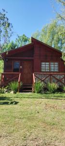 una pequeña casa de madera con un campo de hierba delante de ella en Cabañas Los Patricios, en Colón