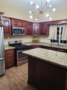 a kitchen with wooden cabinets and granite counter tops at Quiet Oasis It's spacious and elegantly designed in Chaguanas
