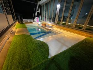 LampangAiko poolvilla的建筑物侧面有一个长满绿草的游泳池。