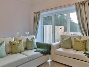 Una sala de estar con un sofá y una ventana grande. en Cur Cottage - Uk7809, en Coirantee