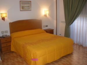 a bedroom with a bed with a yellow bedspread at Hotel Elena María in Granada