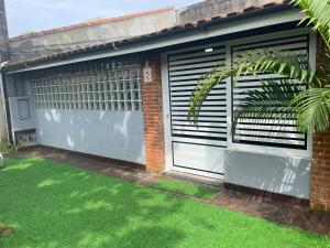 イタニャエンにあるCasa em Itanhaém Pé na Areia ! A 100 metros do marの門と芝生の庭付きガレージ