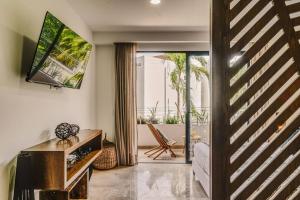 Una sala de estar con un televisor en la pared y un sofá. en Sunrise Studio with Fast-WIFI, Rooftop Pool, Spa, en Tulum