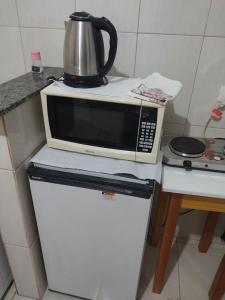 a microwave oven sitting on top of a refrigerator at Espaço Rafael kit net 6 in Maringá