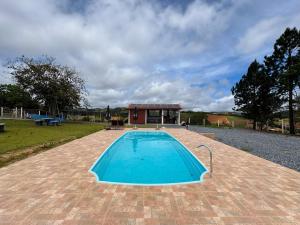 a swimming pool with a house in the background at Sítio Terra Sertaneja - Chalé Um Sonhador in Piedade