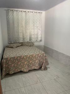 ein Schlafzimmer mit einem Bett mit einer Bettdecke und einem Fenster in der Unterkunft Quarto casal in Trindade