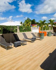 a group of chairs and an umbrella on a wooden deck at Evasion en plein cœur de la ville Studio Jacuzzis Sauna et piscine au centre de Port-Louis in Port-Louis