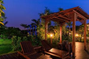 a wooden deck with two chairs and a gazebo at Baan Kiangnam Pattaya Resort in Ban Pong