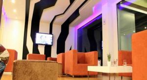 a lobby with orange chairs and a tv on a wall at The One Hotel in Bung Kan