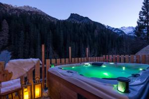 a hot tub in a backyard with a fence and mountains at Stelvio Residence in Trafoi