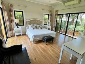 a bedroom with a bed and a table and windows at Pool Villa at Chivani Pattaya by Payaa International in Ban Nong Chap Tao