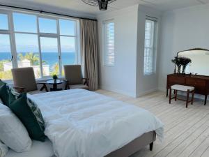 a bedroom with a bed and a desk and windows at Davley House, St James Kalk Bay in Cape Town