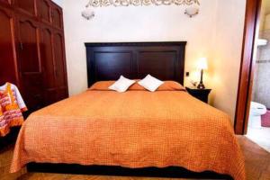 ein Schlafzimmer mit einem großen orangenen Bett mit zwei Kissen in der Unterkunft Depa Kala in Oaxaca de Juárez