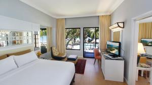 a bedroom with a white bed and a desk with a computer at Holiday Villa Resort & Beachclub Langkawi in Pantai Cenang