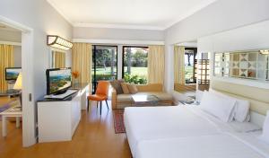 a bedroom with a white bed and a living room at Holiday Villa Resort & Beachclub Langkawi in Pantai Cenang