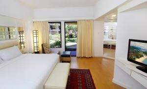 a bedroom with a white bed and a television at Holiday Villa Resort & Beachclub Langkawi in Pantai Cenang