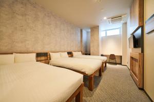 a room with three beds and a flat screen tv at EIGHT POINT INN Kanazawa in Kanazawa