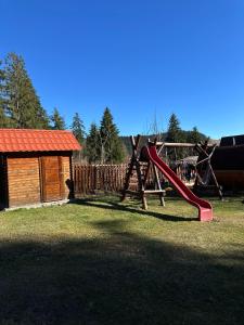 a playground with a red slide in a yard at Casa Moldovan in Izvoru Mureşului
