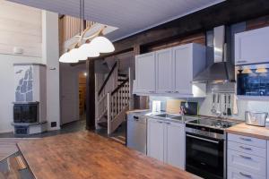 a kitchen with white cabinets and a wooden counter top at Koskikara in Äkäslompolo