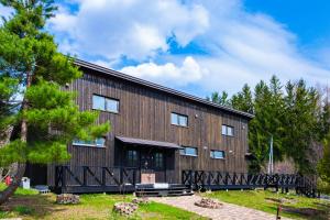 a large wooden building with trees in the background at FamB in Nakafurano