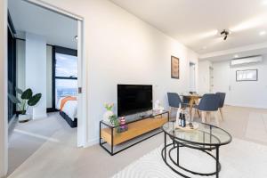 a living room with a television and a dining room at Luxury Collins St Apartment- 2BR w Balcony- High Floor in Melbourne