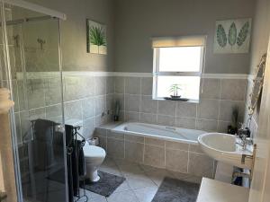 a bathroom with a tub and a toilet and a sink at Somerset Wineland Apartments & Wellness in Somerset West