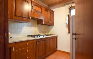 a kitchen with wooden cabinets and a stove top oven at Beautiful Home In Santa Teresa Di Riva in Capo Mulini
