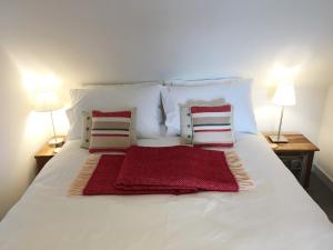 a white bed with two pillows and a red blanket on it at The Apostles in Catacol