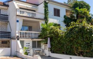 a white house with a table and an umbrella at 2 Bedroom Amazing Apartment In Malinska in Malinska