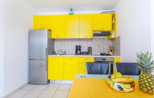 kuchnia z żółtymi szafkami i stołem z misą owoców w obiekcie 3 Bedroom Cozy Apartment In Dobrinj w mieście Dobrinj