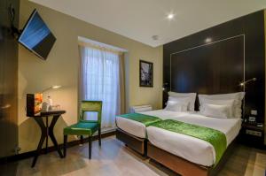 ein Hotelzimmer mit einem großen Bett und einem Stuhl in der Unterkunft behotelisboa in Lissabon