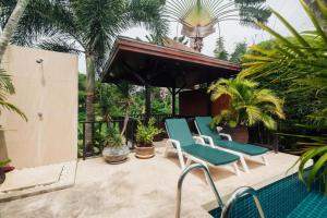 een patio met 2 stoelen en een zwembad bij Chaba Pool Villa in Nai Harn Beach
