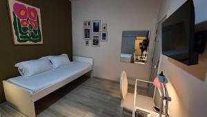 a small room with a bed and a tv at IHOC - Phuket OldTown in Ban Lo Long
