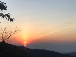 a sunset on a hill with the sun in the sky at บ้านต้นไม้แม่กำปอง Baan TONMAI MAEKAMPONG in Chiang Mai