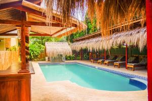 圣胡安Wilcon Guesthouse Catulayan的一个带草伞的度假村内的游泳池