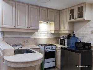 マニラにあるCondo with seaview in malateのキッチン(白いキャビネット、コンロ、シンク付)