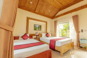 two beds in a room with a window at Tam Coc Green Garden Bungalow in Ninh Binh