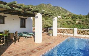 a house with a swimming pool and a table and chairs at 2 Bedroom Amazing Home In Frigiliana in Frigiliana