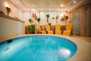 a large swimming pool in a room with yellow chairs at Rasstal Spa Hotel in Naberezhnyye Chelny